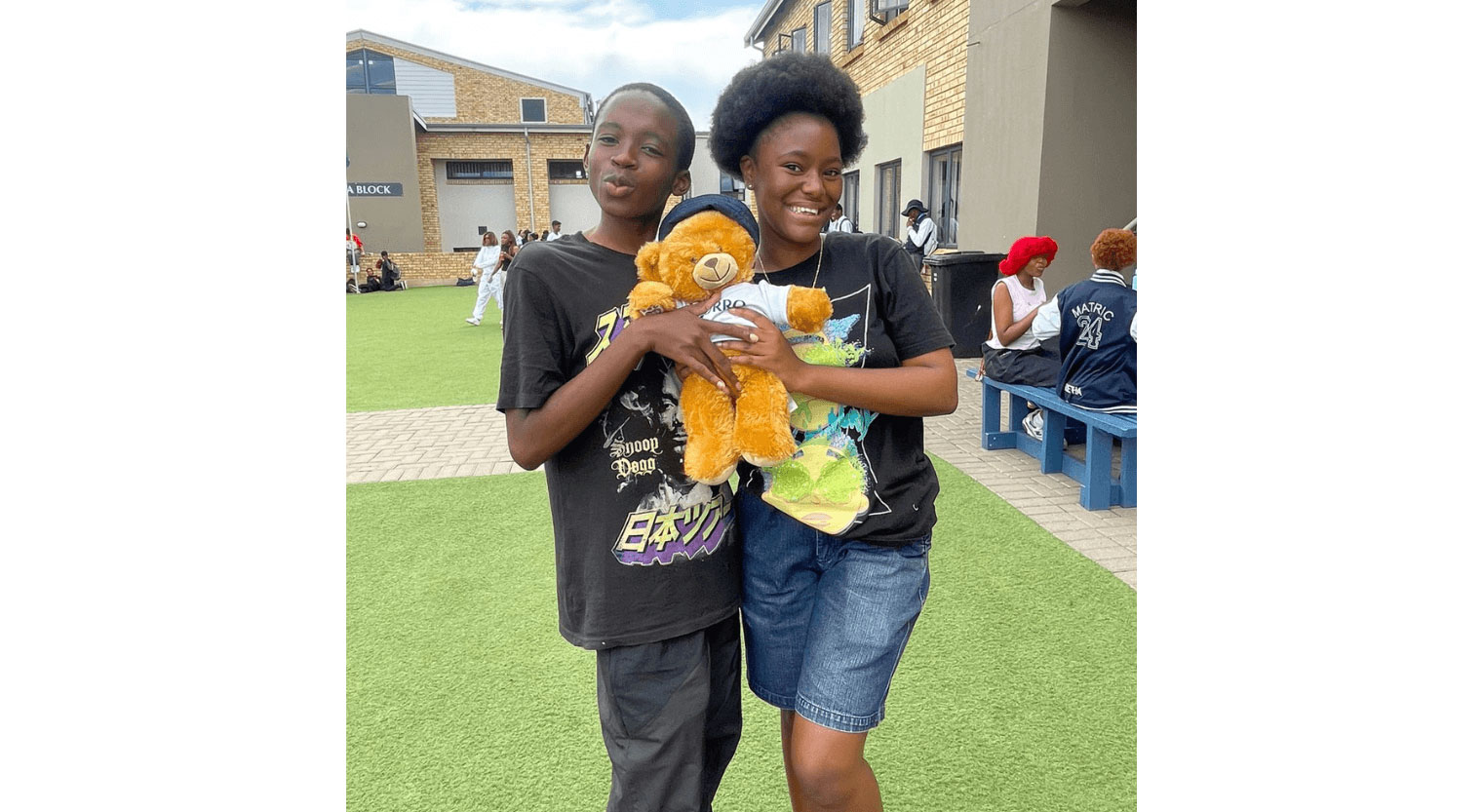 Two high school students standing and holding a stuffed toy bear together